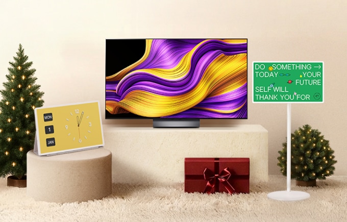 베이지색 배경에 가운데에 단상 위 LG 올레드 TV가 놓여 있고 주변에는 크리스마스 트리, 선물상자, 스탠바이미가 있으며 1월 1일을 가르키는 시계가 왼쪽 단상에 놓인 이미지